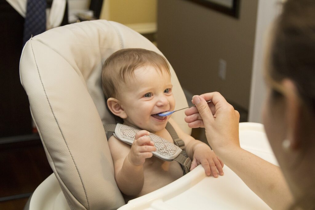 離乳食を食べさせてもらう笑顔の赤ちゃん